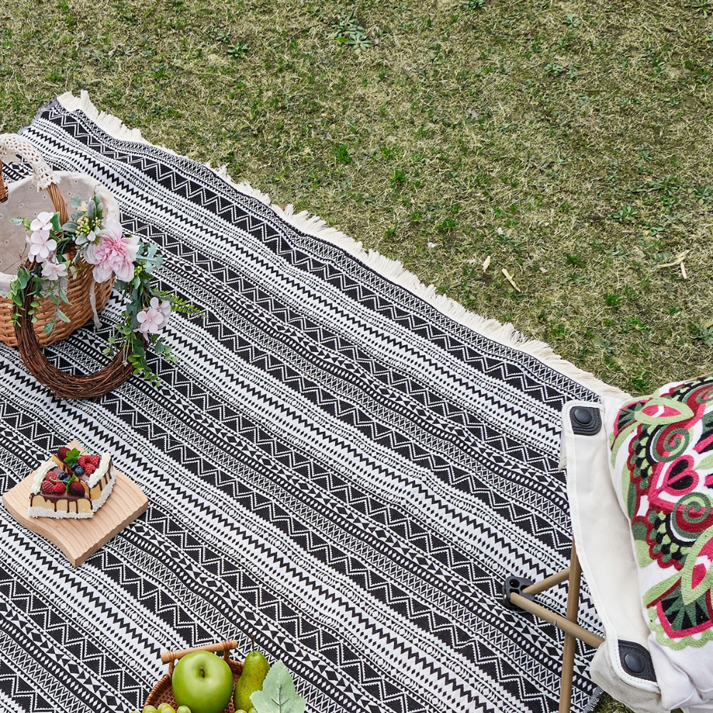 Picknickfilt i bohostil placerad på gräs för avkoppling utomhus
