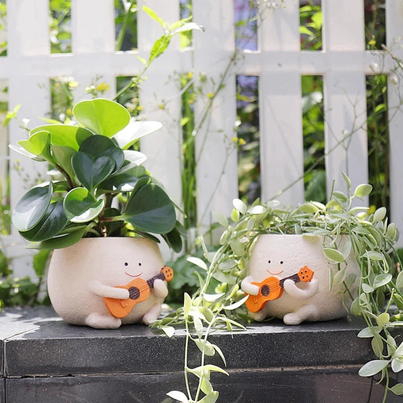 Närbild av blomkruka i harts med ansiktsdesign och rund form