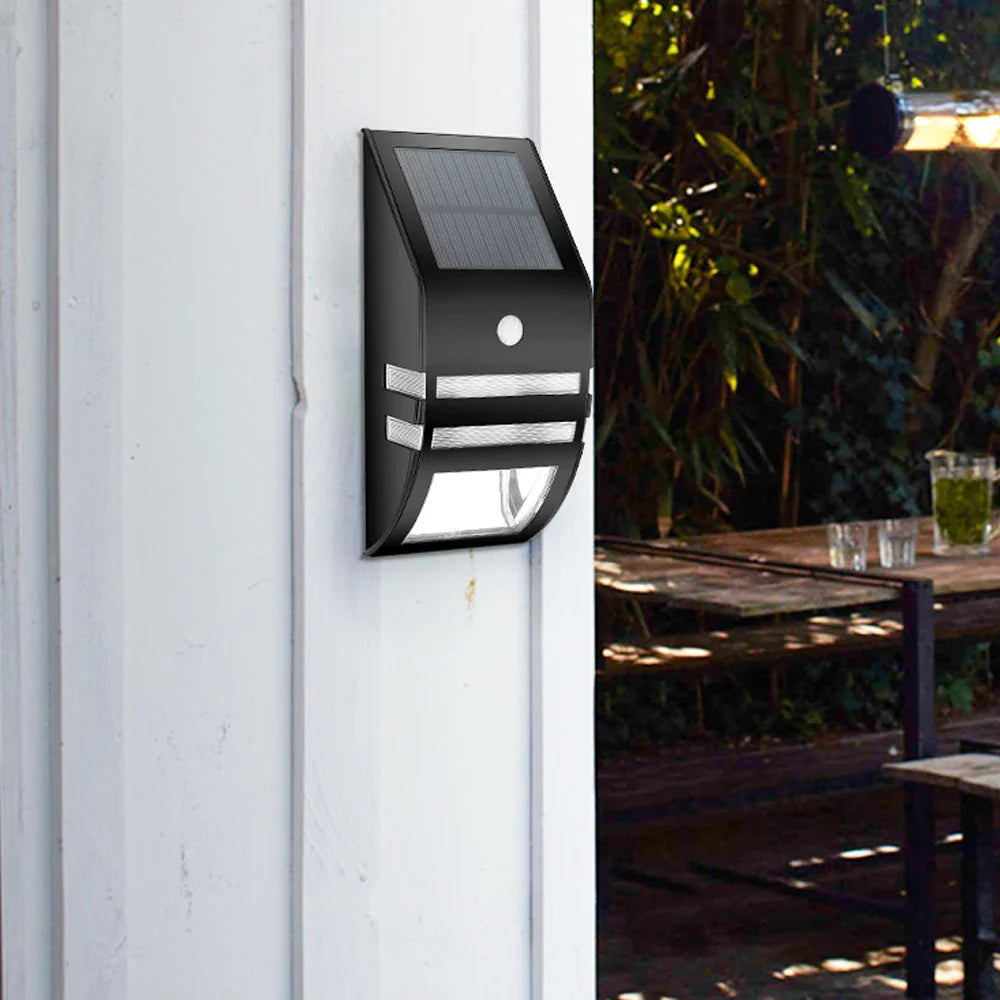 Närbild på solcellsvägglampa som lyser upp fasad och gångväg