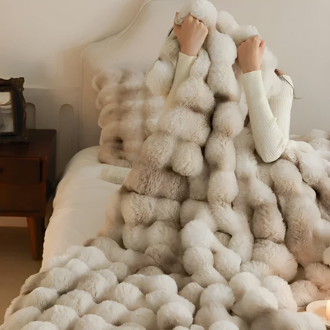 flauschige beigefarbene Decke mit einem strukturierten, blasenartigen Design, die ĂŒber ein Bett drapiert wird, um einen gemĂŒtlichen und luxuriösen Look zu erzielen
