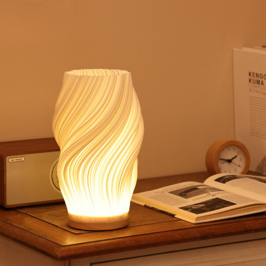 Bordslampa med böljande form placerad på sängbord