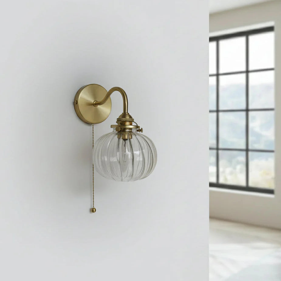 Detalj av vägglampa i glas med guldfärgade metalldelar
