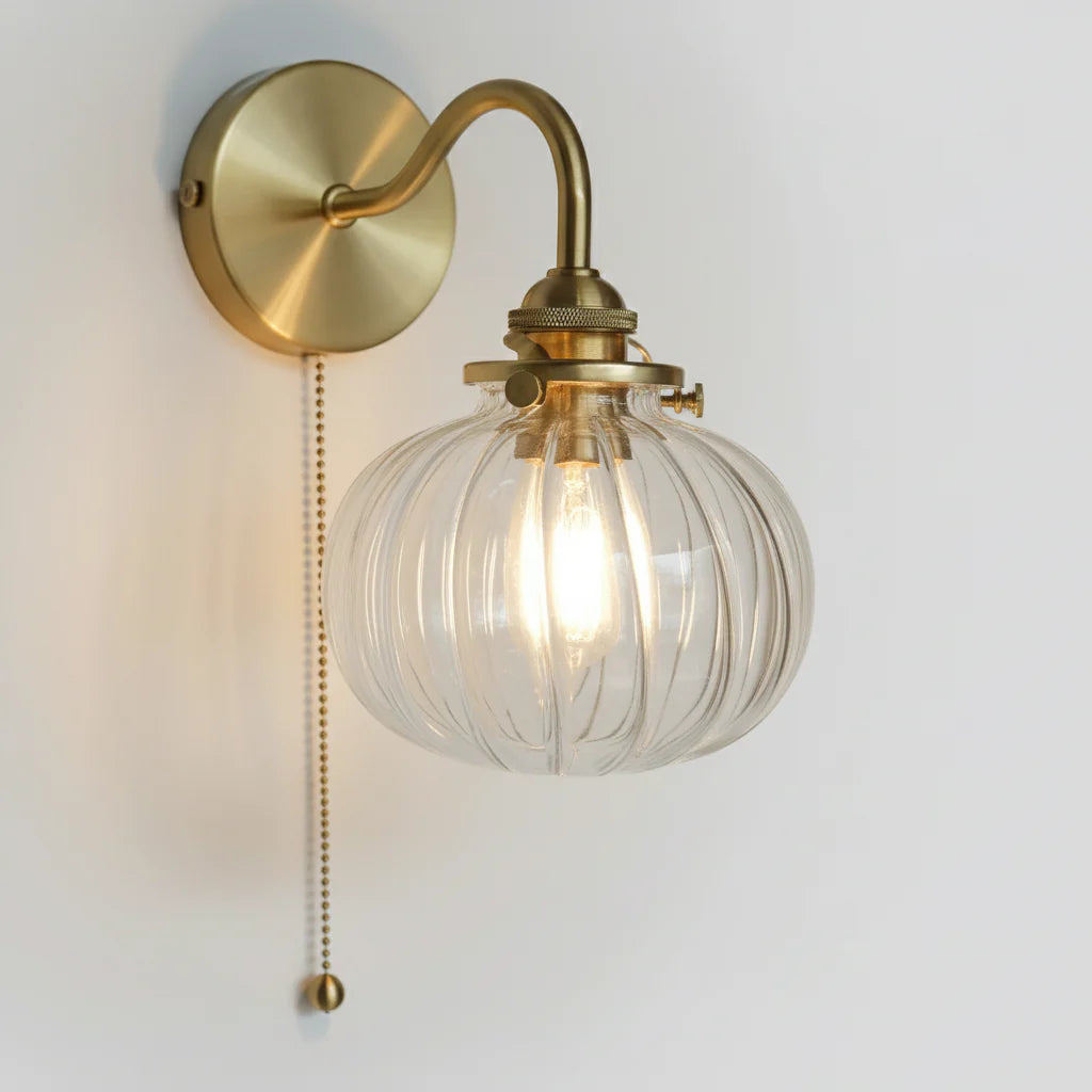 Sidovy av vägglampa i glas och guldfärgad metall