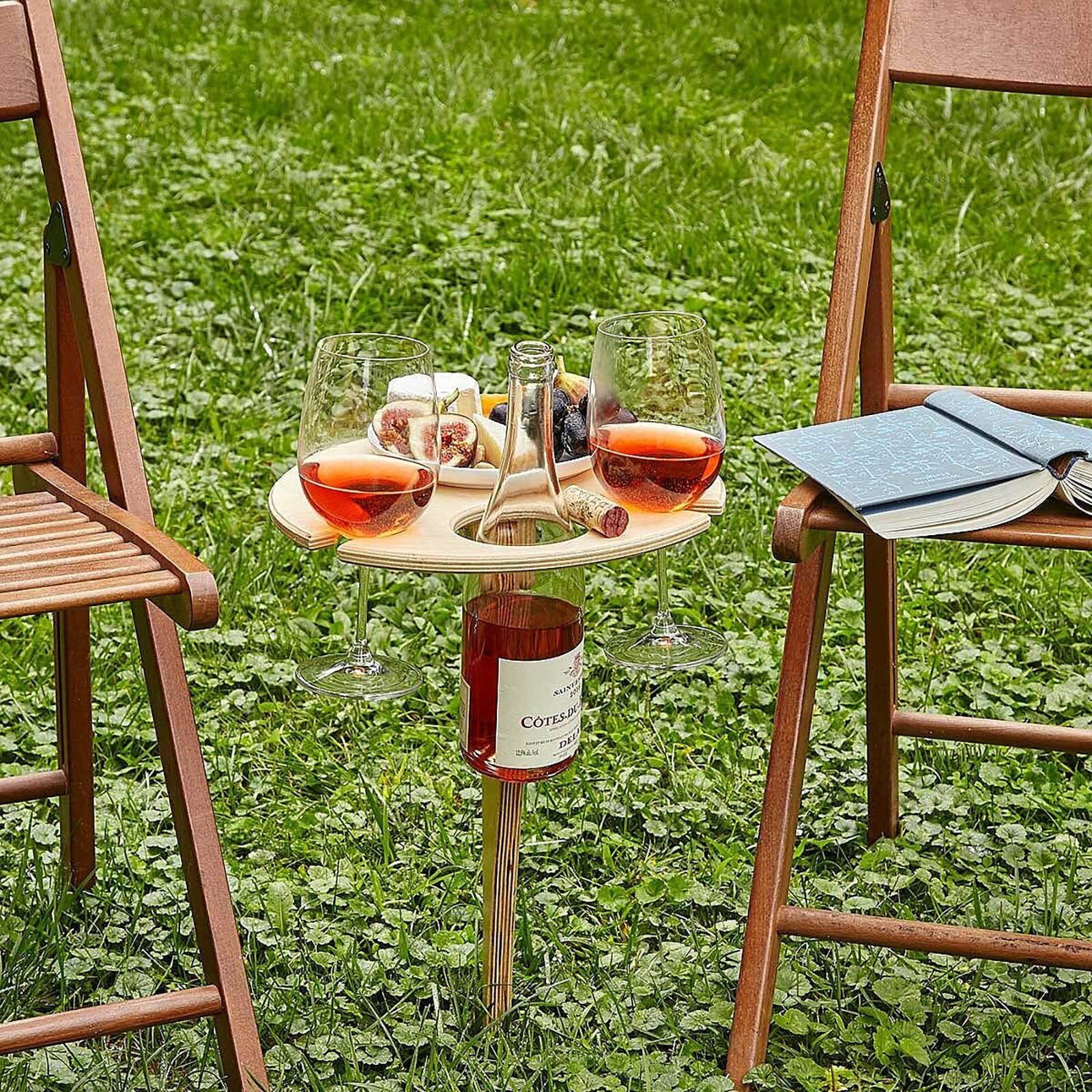 Träbord för picknick uppfällt på marken med plats för vinflaska och glas