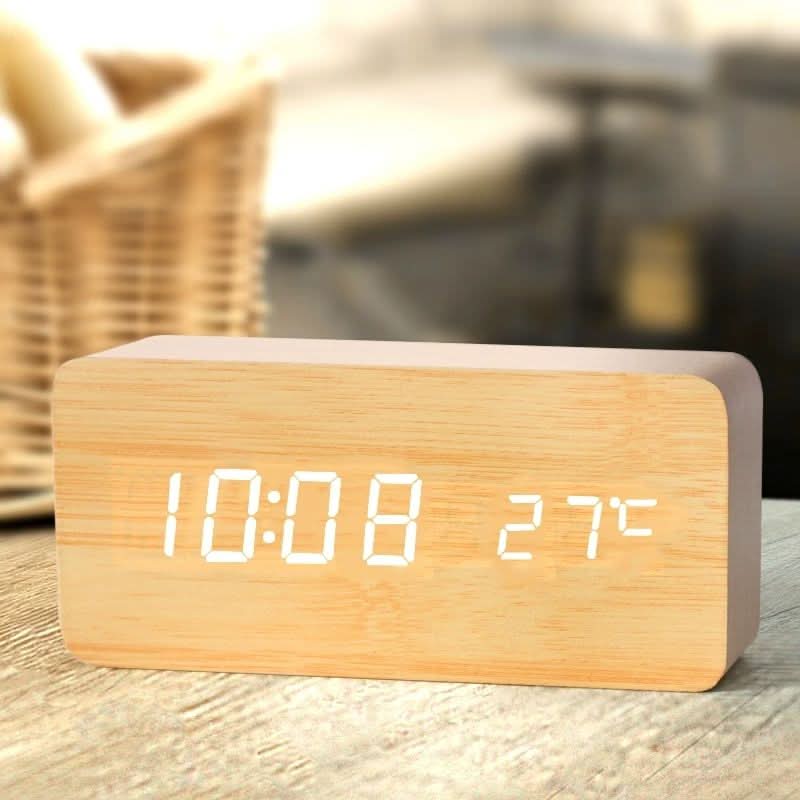 Digital väckarklocka med LED-display och trälook på ett bord