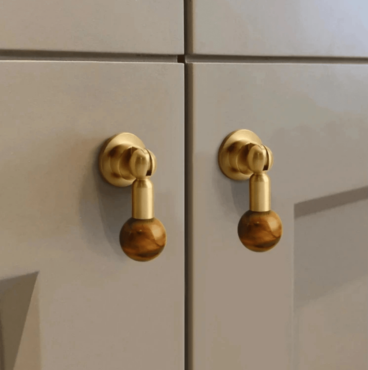 Närbild av möbelknopp i mässing med bärnstensfärgad kristall