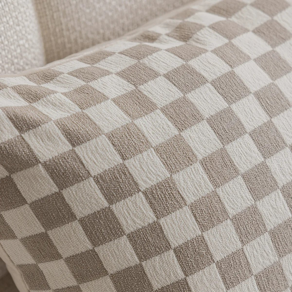 Närbild av dekorationskuddens tåliga tyg och beige rutor
