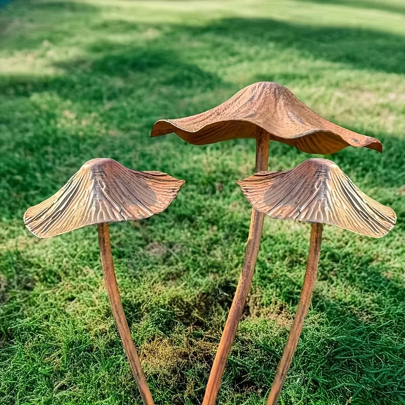 Tre trädgårdsskulpturer i metall med rostlook formade som svampar